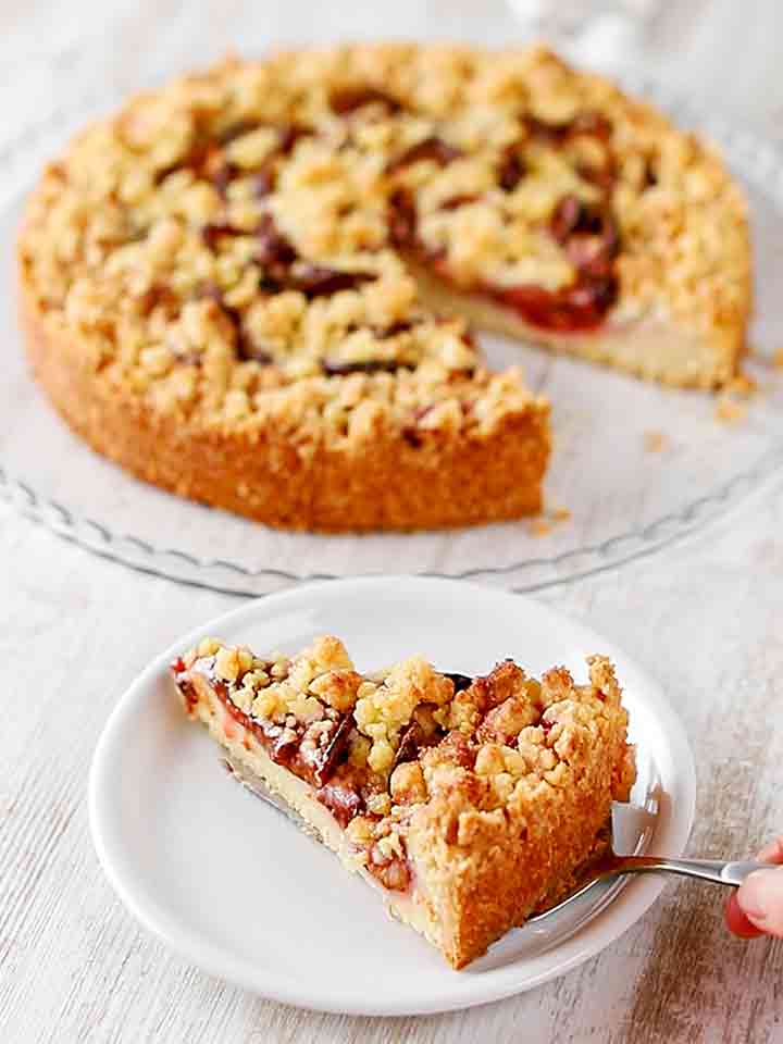 Veganer Pflaumenkuchen mit Streuseln und Pudding wird serviert