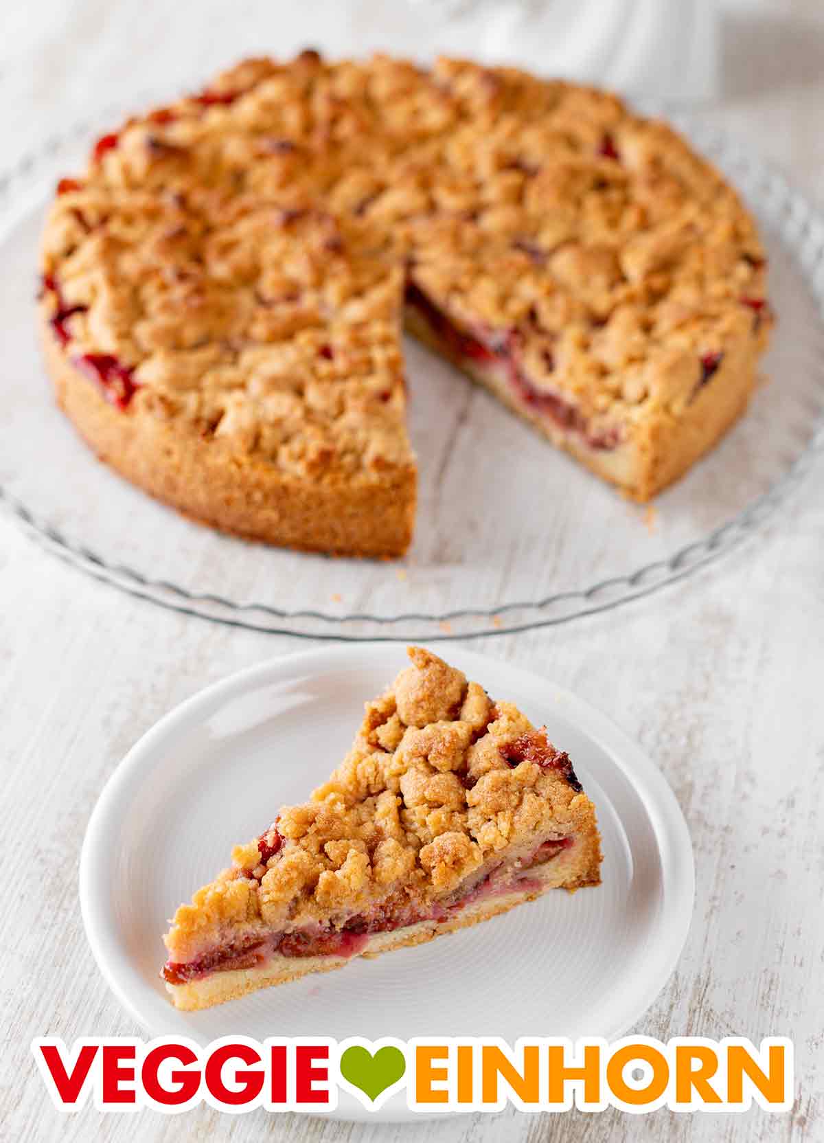 Der vegane Mürbeteig Kuchen mit Pflaumen und Streuseln wird serviert. Veganer Zwetschgenkuchen mit Zimtstreuseln auf einer Tortenplatte und ein Stück auf einem Kuchenteller