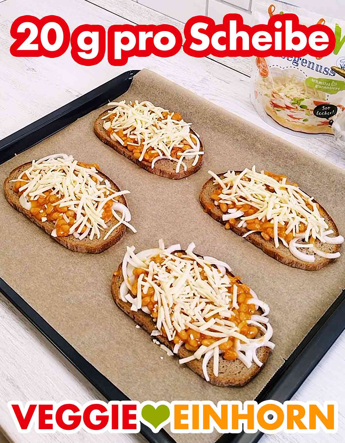 Pro Brotscheibe ungefähr 20 g veganer Reibekäse Vier Scheiben Graubrot mit Zwiebeln, Baked Beans und veganem Reibekäse auf einem Backblech