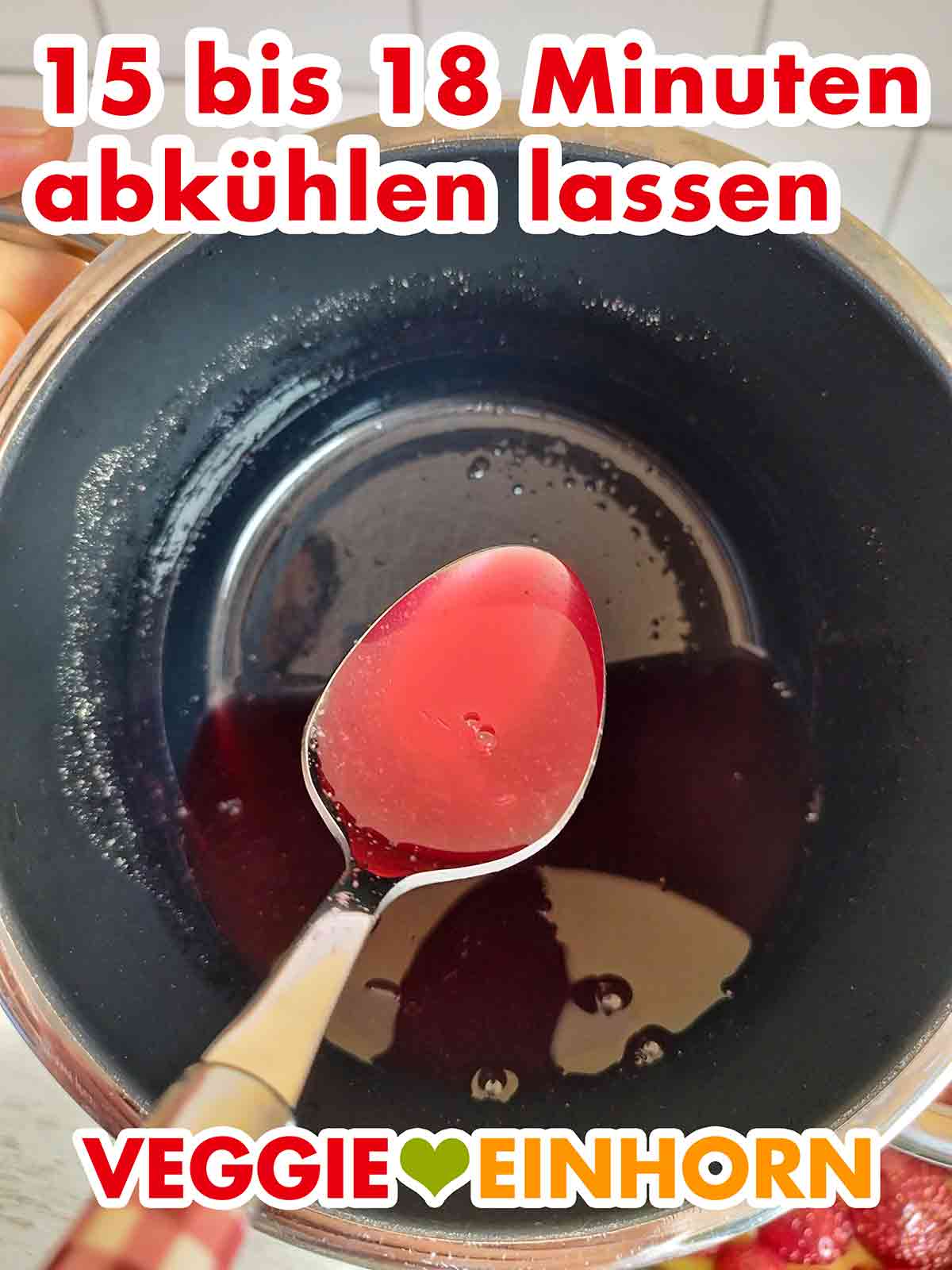 Der Tortenguss mit Agar-Agar muss auf 40°C abkühlen. Abgekühlter veganer roter Tortenguss auf einem Esslöffel