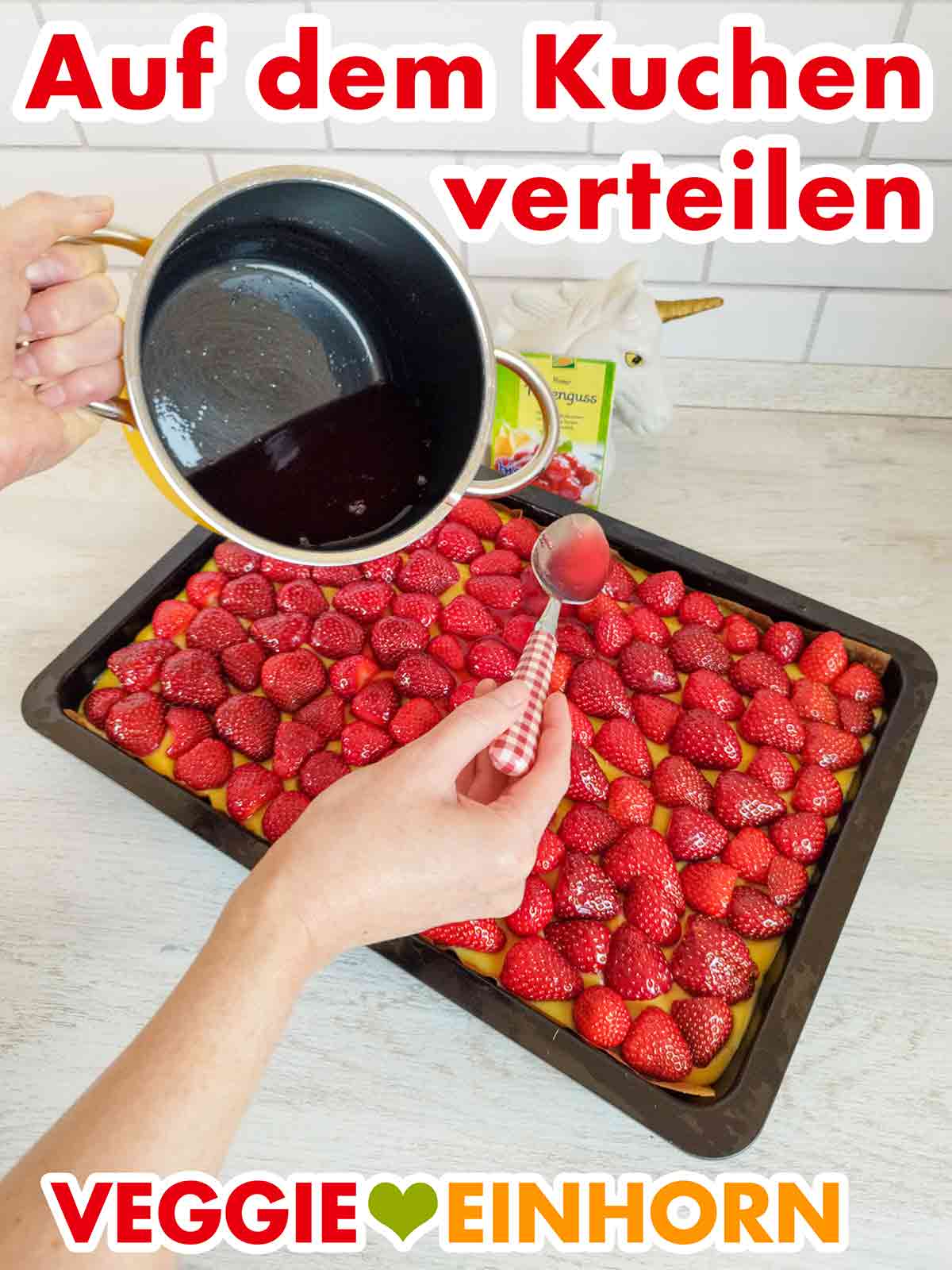 Auftragen des veganen roten Tortengusses von Biovita Der rote Tortenguss von Biovita wird auf einem veganen Erdbeerkuchen vom Blech verteilt.