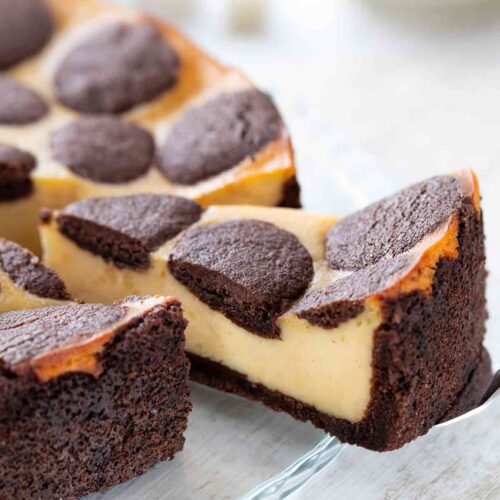 Veganer russischer Zupfkuchen mit cremiger Füllung und schokoladigem Mürbeteig, angeschnitten auf einer Glasplatte.