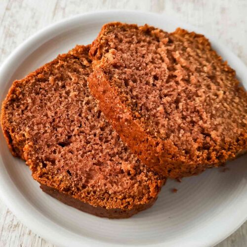 Zwei saftige Scheiben veganer Rührkuchen mit Apfelmus auf einem weißen Teller.