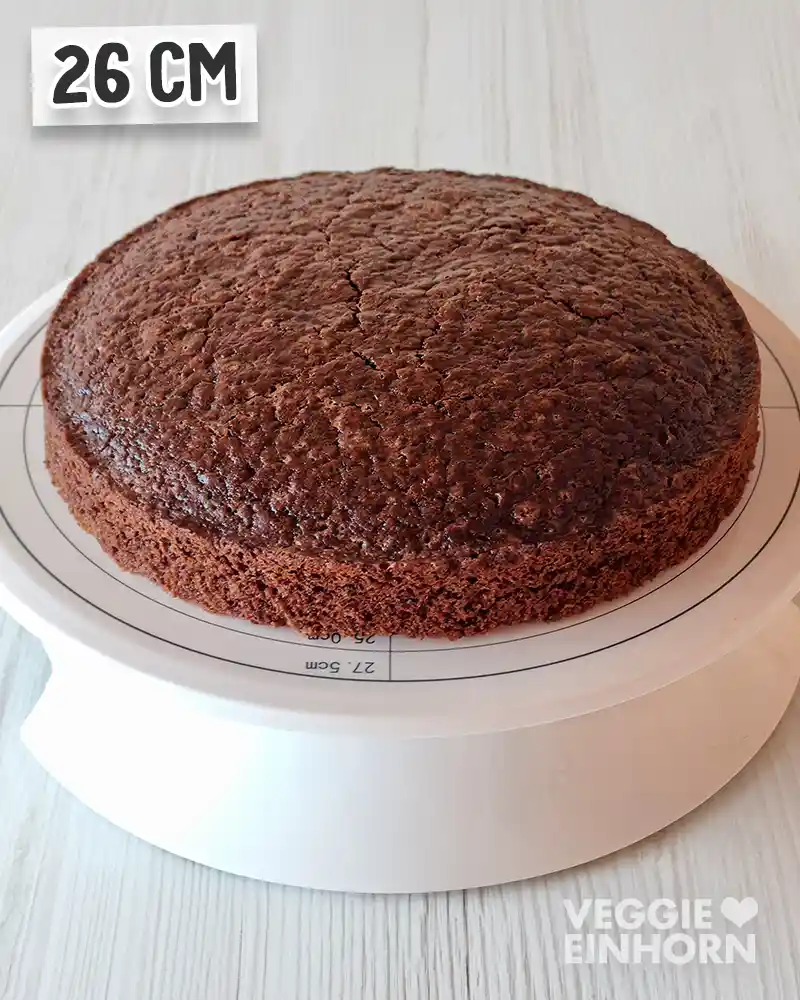 Frisch gebackener veganer Schokobiskuit als runder Tortenboden auf einer Drehplatte.