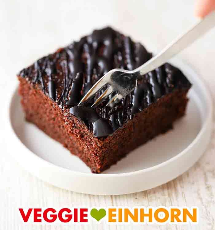 Der vegane Schokokuchen vom Blech schmeckt sehr gut mit Schokoglasur. Ein Stück Schoko Blechkuchen mit einer Gabel