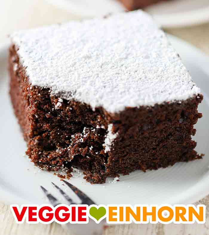 Der Kuchen ist saftig und lecker. Ein Stück saftiger veganer Schoko Blechkuchen mit Puderzucker.