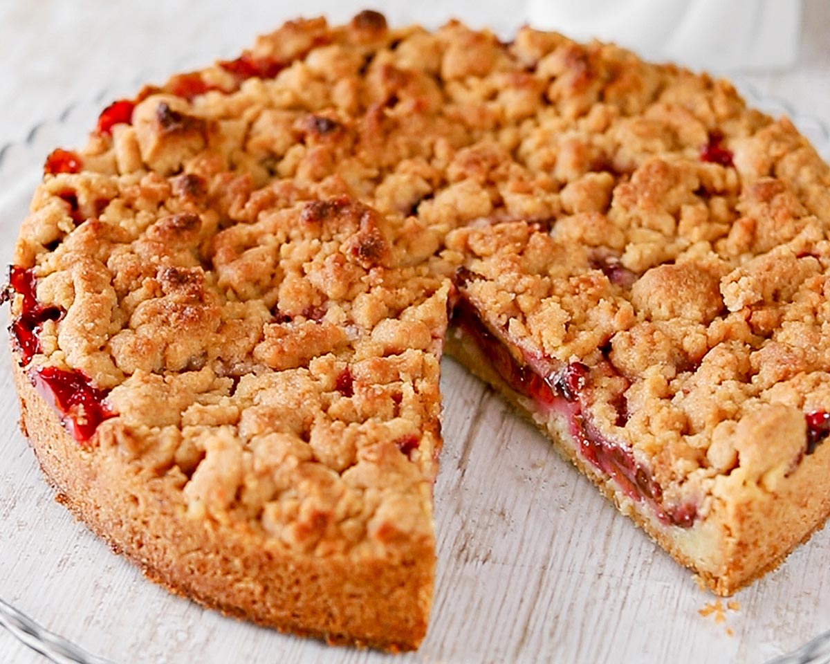 Veganer Pflaumenkuchen mit Zimtstreuseln auf einer Tortenplatte