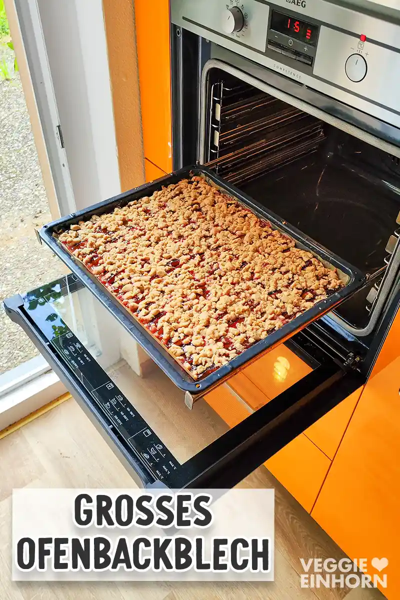 Ein großes Ofenbackblech mit veganem Zwetschgenkuchen mit Zimtstreuseln, das gerade aus dem Backofen gezogen wurde. 