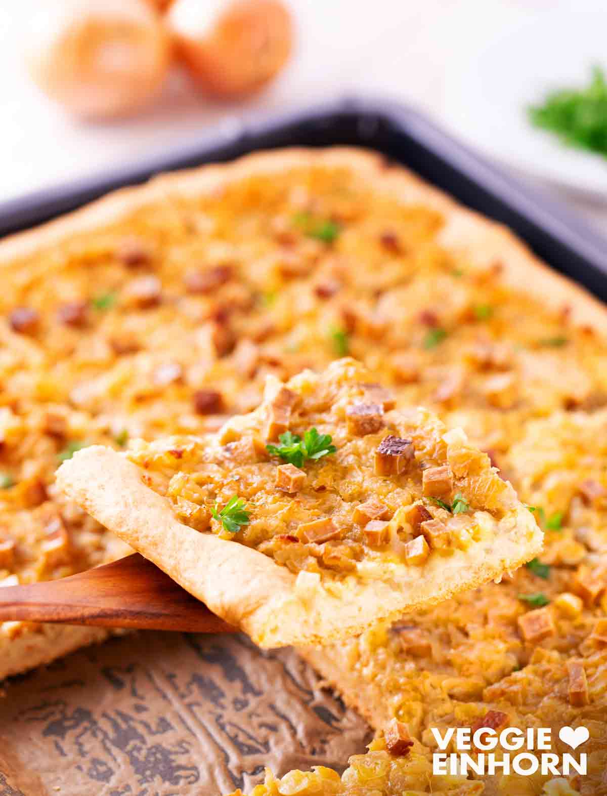 Veganer Zwiebelkuchen vom Blech mit Hefeteig Ein Stück veganer Zwiebelkuchen vom Blech und im Hintergrund ein Blech veganer Zwiebelkuchen