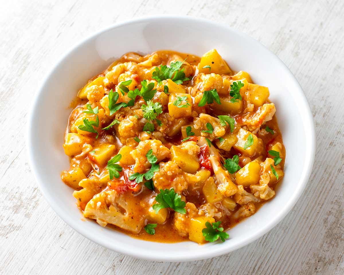 Aloo Gobi ist ein veganes indisches Curry mit Blumenkohl und Kartoffeln. Teller mit Aloo Gobi