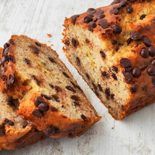 Anschnitt von veganem Bananenbrot mit vielen Schokotropfen auf einem hellen Untergrund.