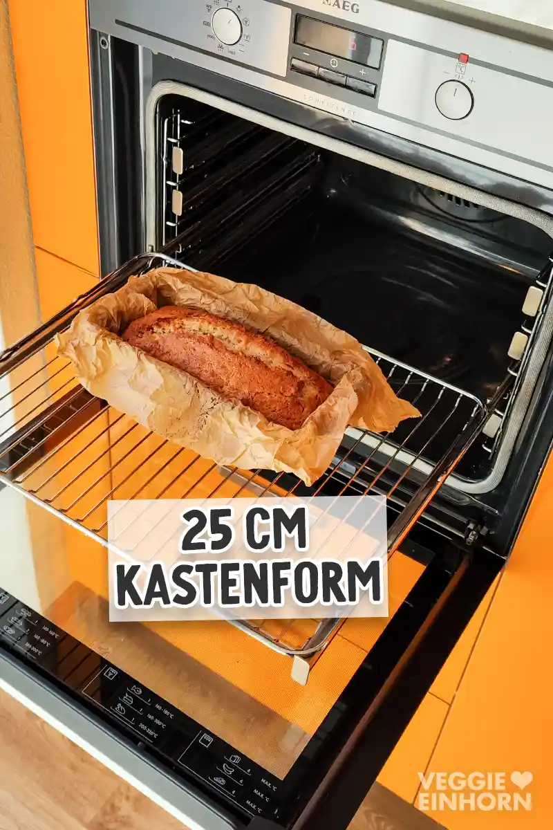 Veganes Bananenbrot mit Walnüssen in einer mit Backpapier ausgelegten Kastenform im geöffneten Backofen.