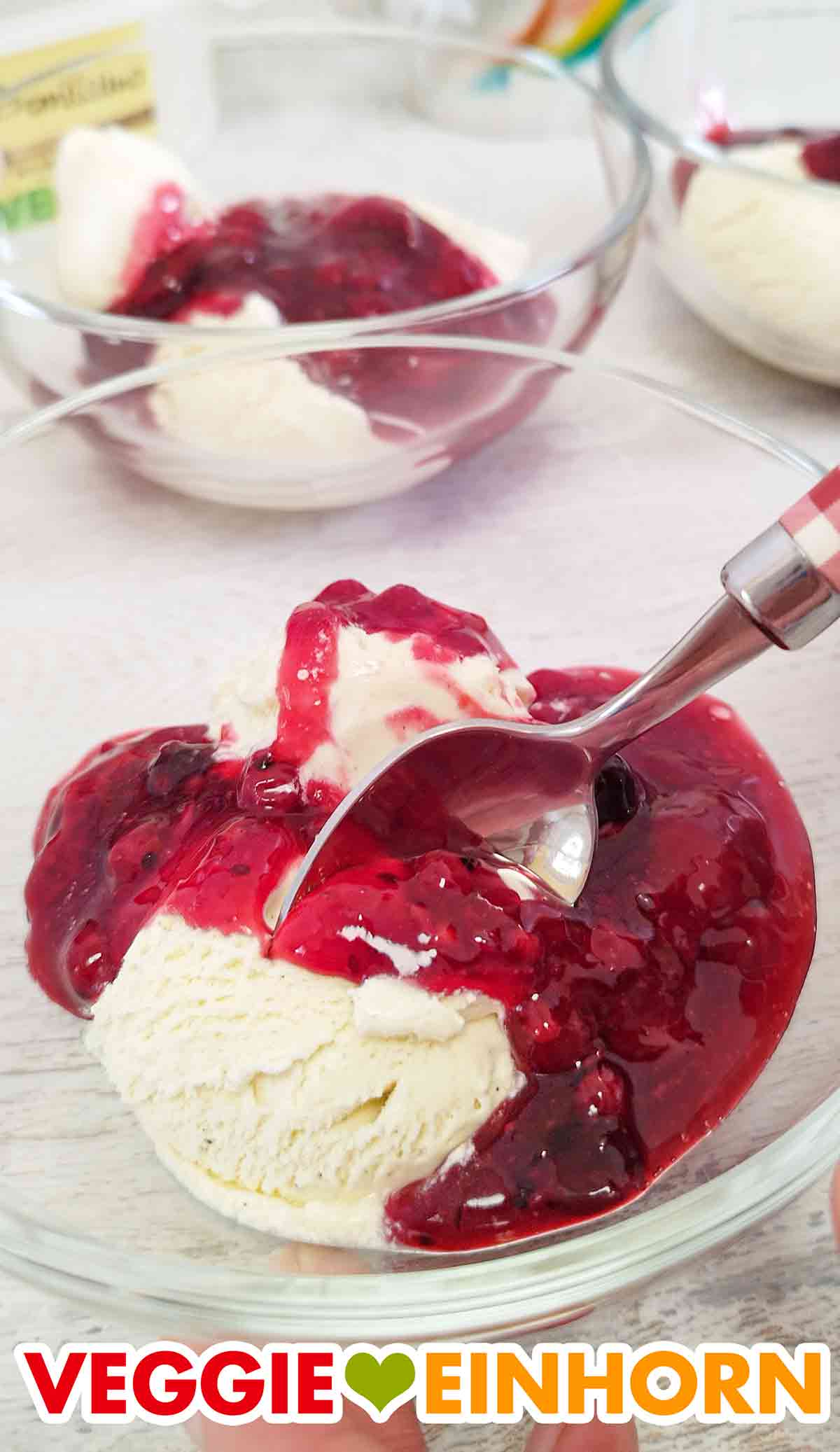 Dessertschale mit einer Kugel veganem Vanilleeis und veganer roter Grütze Nahaufnahme von veganem Cremissimo Eis mit roter Grütze von Dr. Oetker