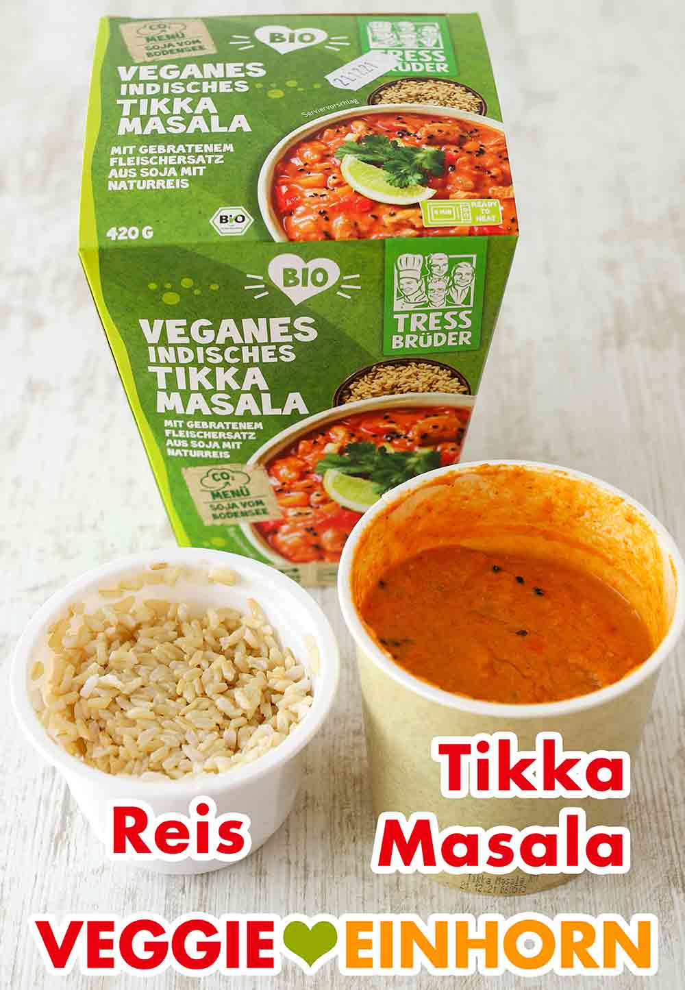 Das Fertiggericht enthält gekochten Naturreis und veganes Tikka Masala. Eine Packung veganes Fertiggericht mit einem Becher Reis und einem Becher Tikka Masala