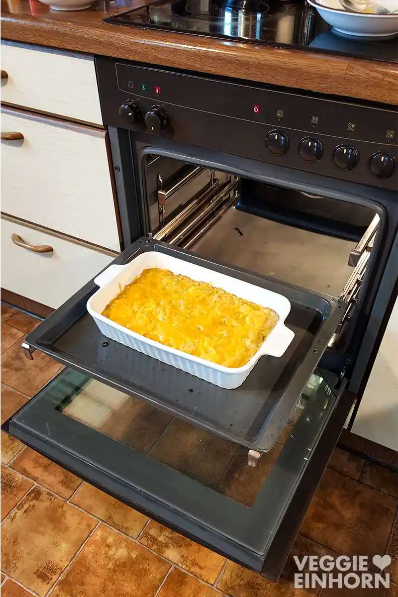 Ein veganes Kartoffelgratin mit veganem Käse im geöffneten Backofen.