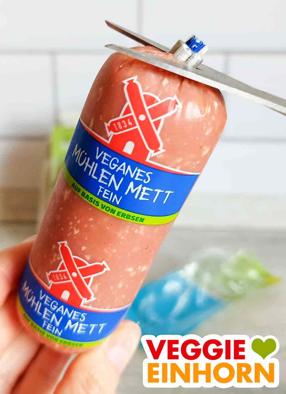 Öffnen des veganen Mühlen Mett Fein von Rügenwalder Die Wursthülle des veganen Mühlen Metts wird mit der Schere geöffnet