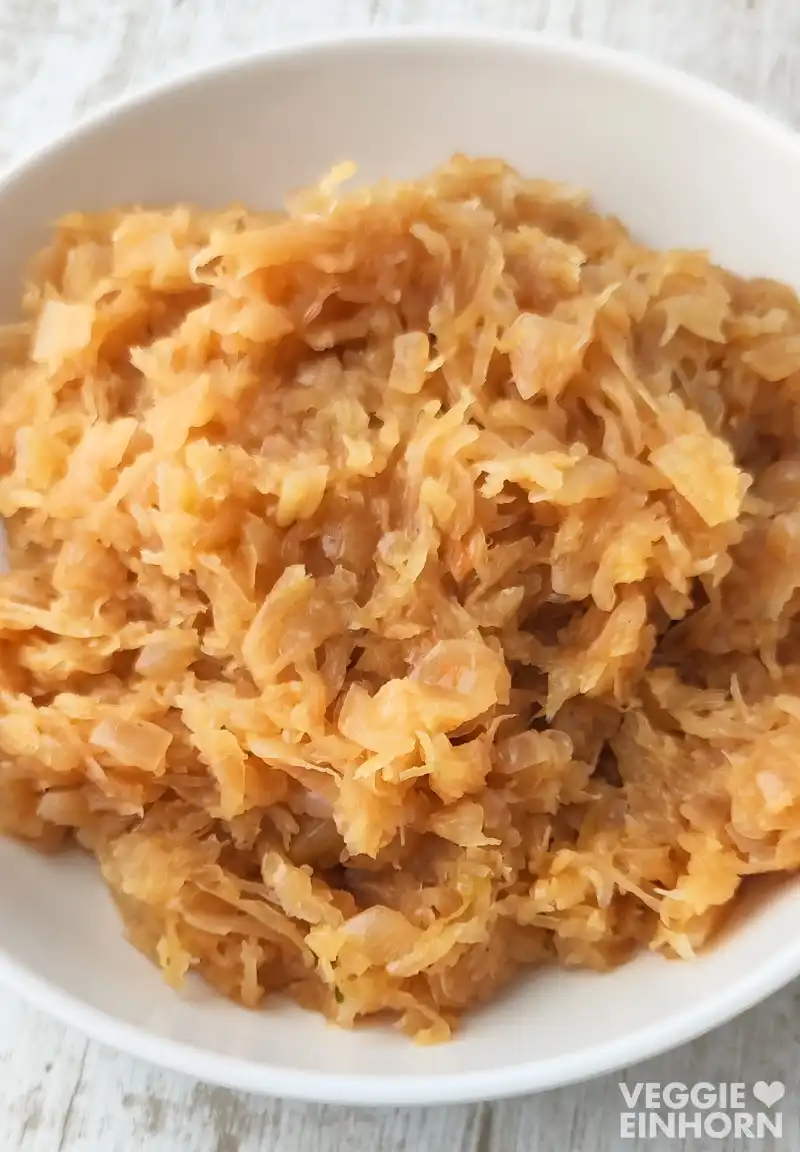 Nahaufnahme von gekochtem veganem Sauerkraut in einer weißen Schüssel.