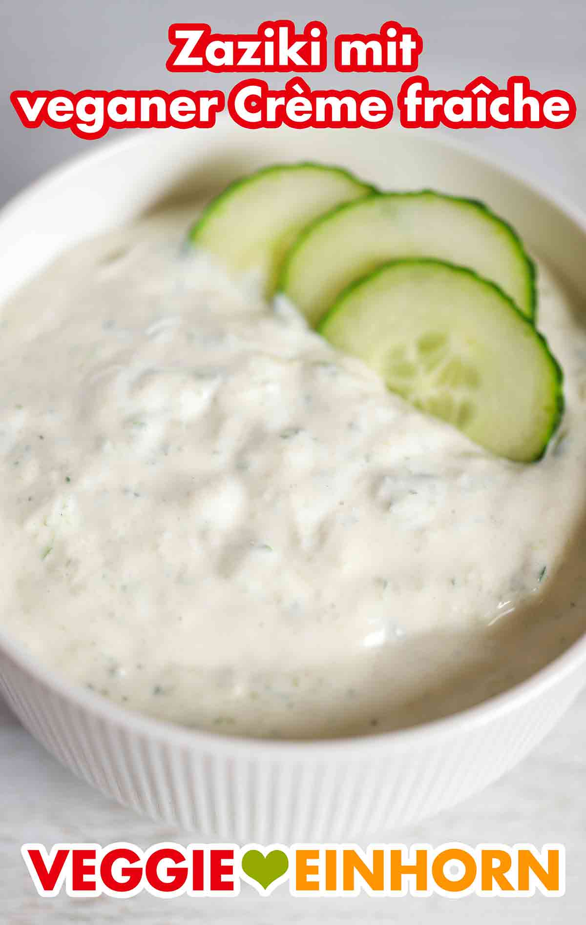Der cremige Zaziki mit Crème fraîche und Sojajoghurt ist vegan und laktosefrei. Eine Schale mit veganem Zaziki und drei Gurkenscheiben