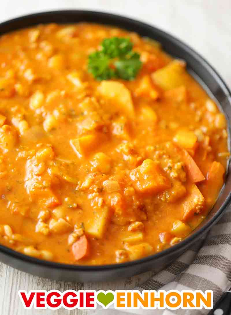 Der kräftige Kürbiseintopf ist vegetarisch und vegan. Ein Teller Kürbiseintopf mit veganem Hack