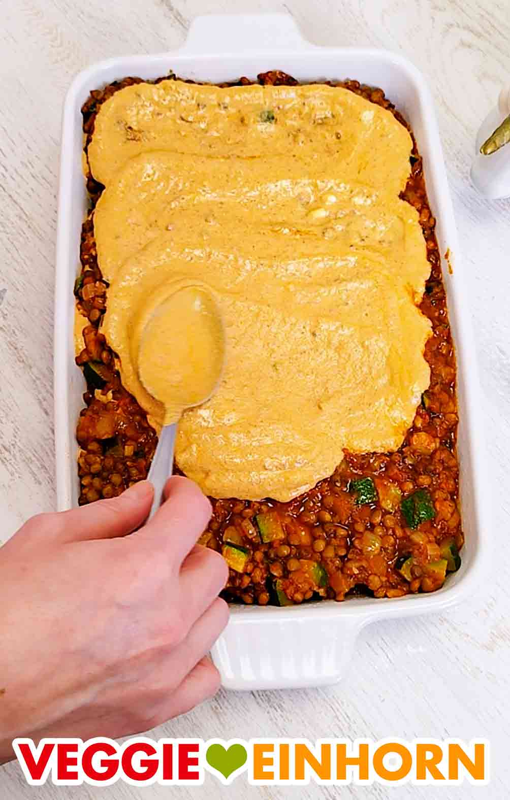Die vegane Frischkäsesoße oben auf der Lasagne verteilen. Die oberste Schicht der veganen Lasagne ist Frischkäse-Pesto-Sauce
