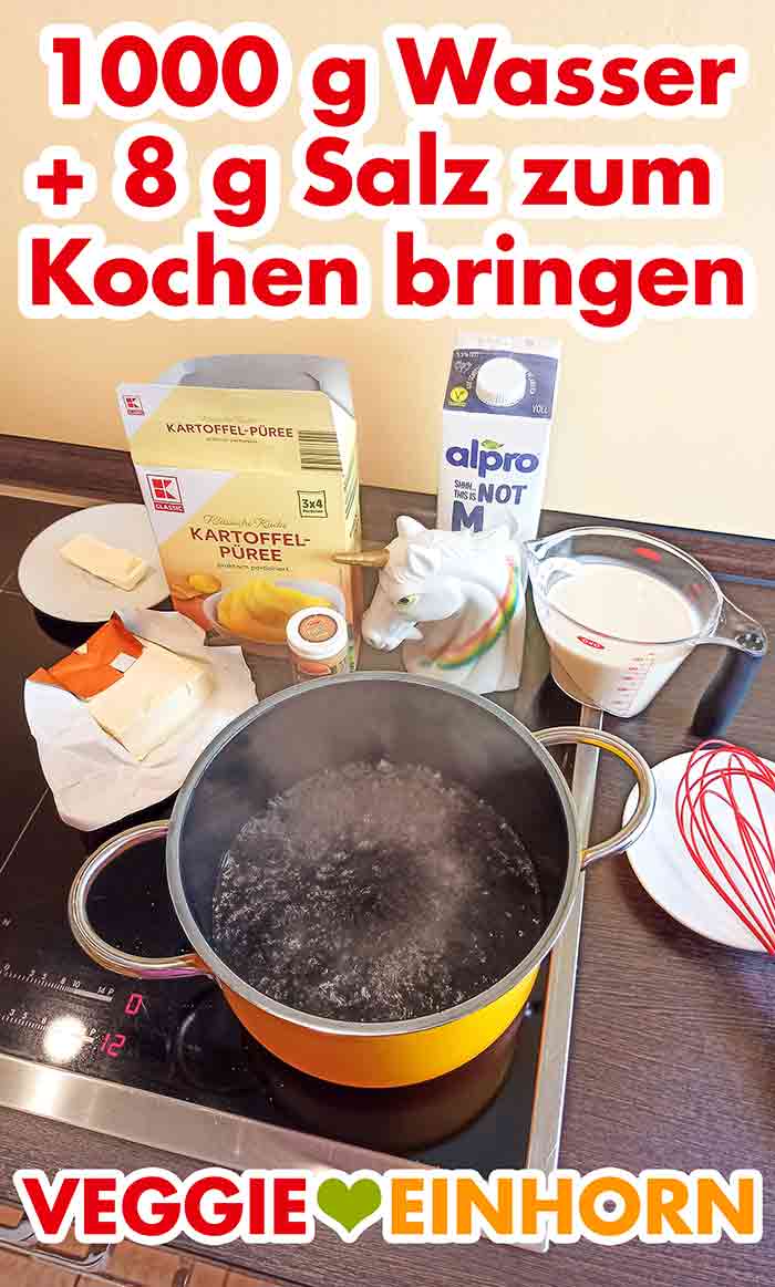 Für das vegane Kartoffelpüree 1000 g Wasser mit 8 g Salz zum Kochen bringen. Ein Topf mit kochendem Wasser und zurecht gestellten Zutaten für das vegane Kartoffelpüree