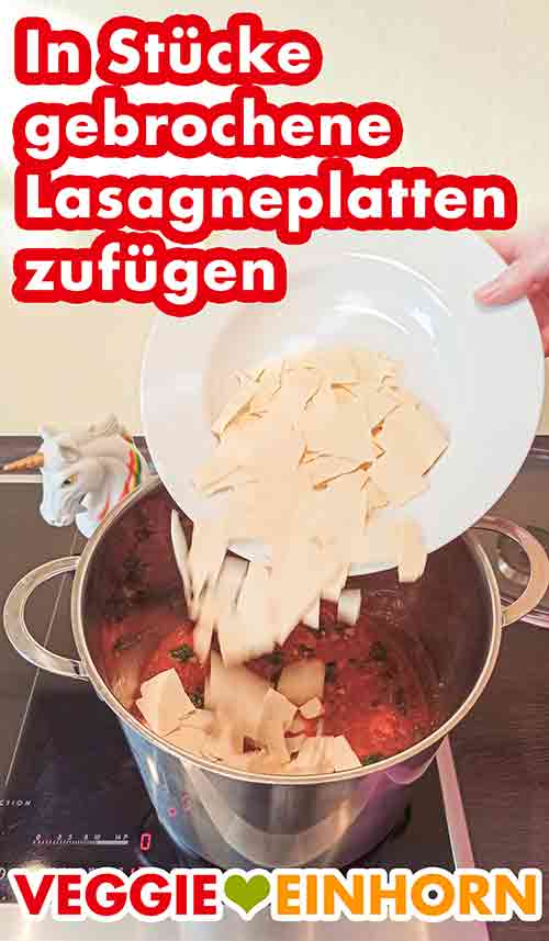 Zufügen der Stücke von Lasagneplatten Die zerbrochenen Lasagneplatten werden in den Topf gegeben