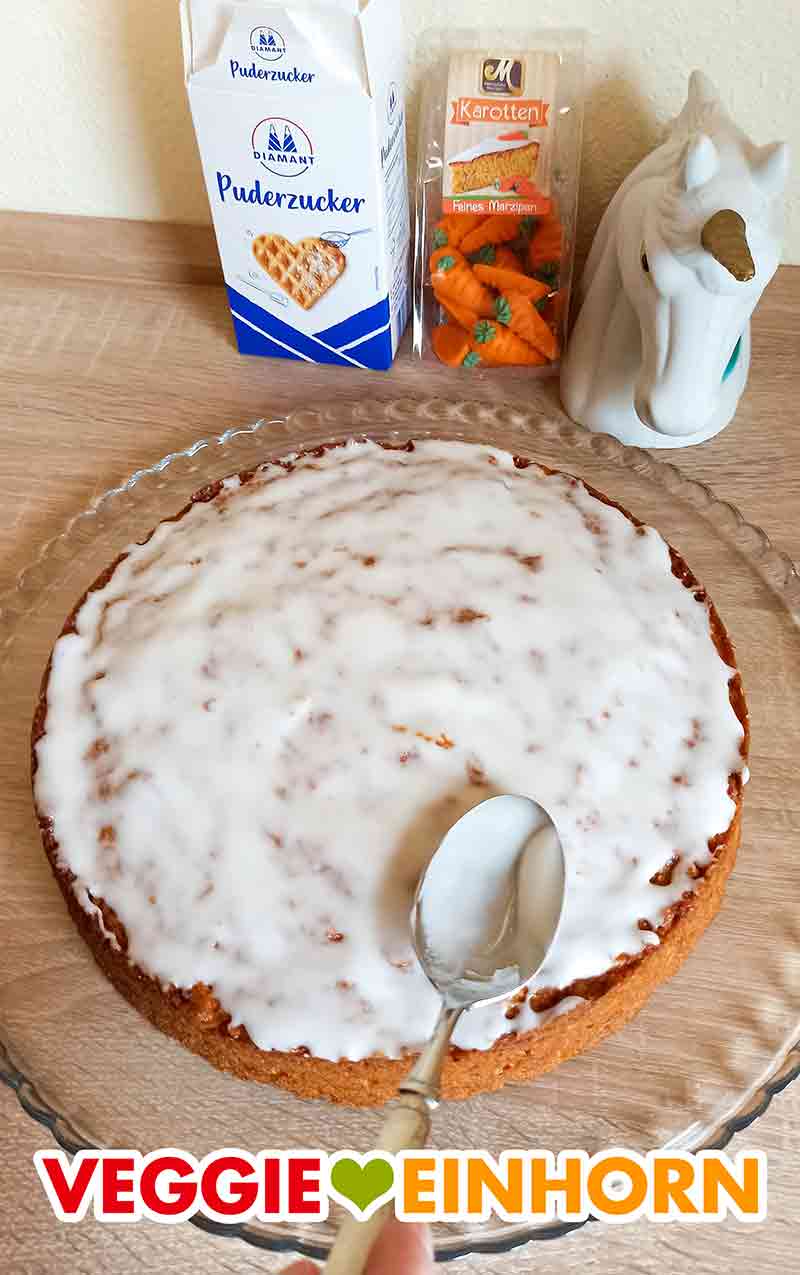 Karottenkuchen mit verteiltem Zuckerguss Der Zuckerguss ist fertig auf dem Karottenkuchen verteilt