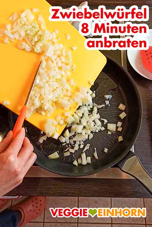 Zwiebelwürfel in das heiße Öl in der Pfanne geben und 8 Minuten anbraten. Zwiebelwürfel werden von einem Schneidebrett in eine Bratpfanne gegeben